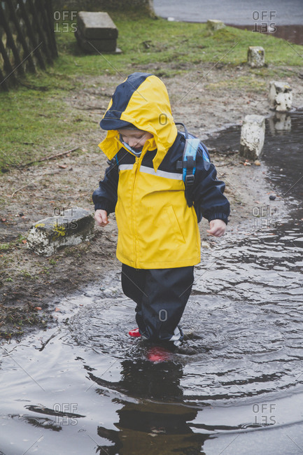 Little boy in a rainsuit exploring a puddle- Sylt- Germany