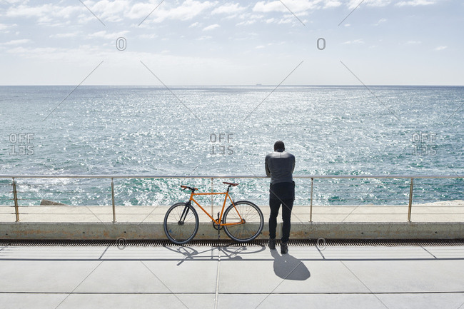 Rear view of man with bike on waterfront promenade