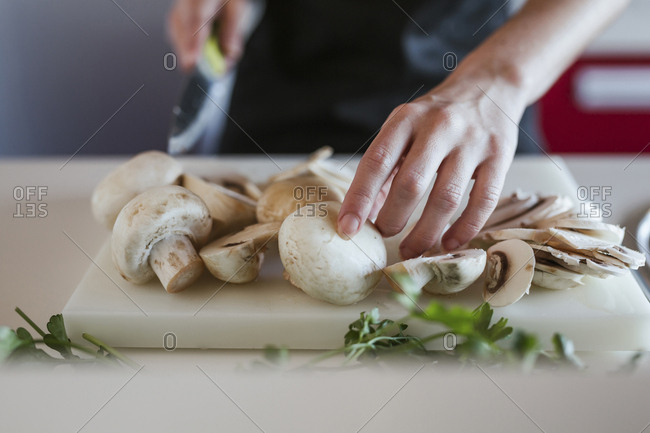 Young woman's hands preparing champignons- close-up