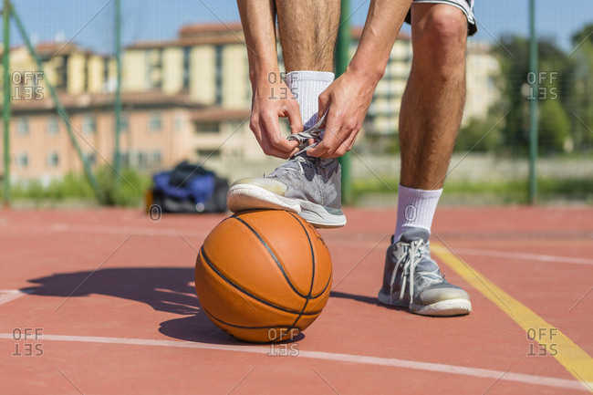 Young basketball player tying shoes