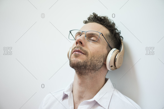 Businessman with closed eyes listening to music with headphones