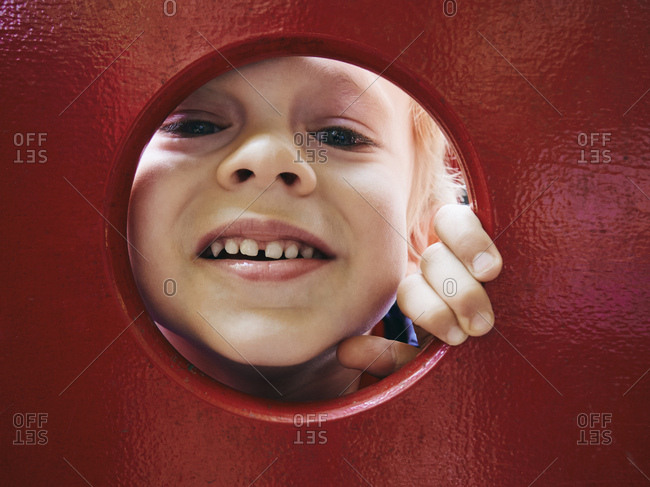Portrait of smiling little boy looking through hole on playground