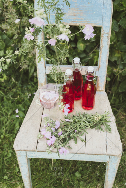 Bottled mallow juice and glass on a chair