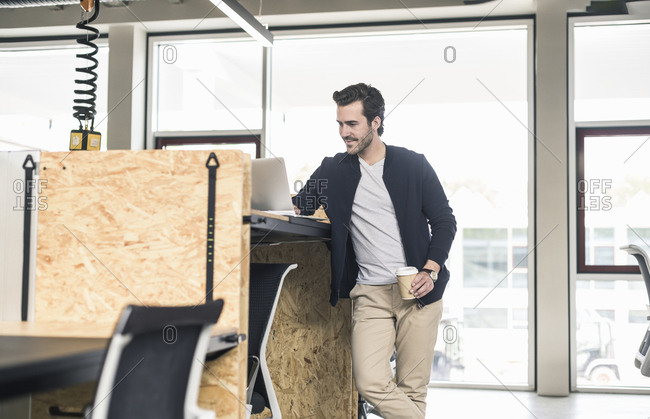 Young Businessman In Modern Office Using Laptop On High Desk