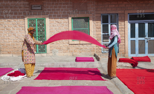 Jaipur, India - October 27, 2011: Two textile workers folding and lying cloth to dry in sun