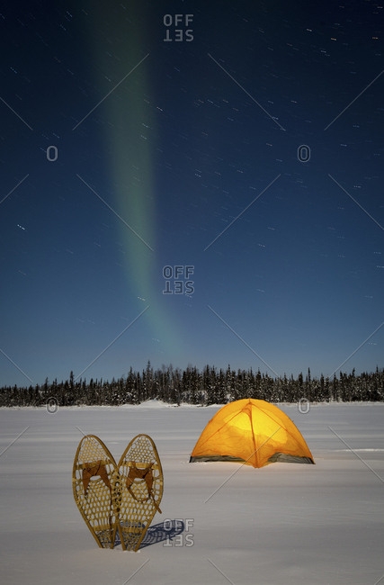 Aurora Borealis above tent and snow shoes, Yellowknife.