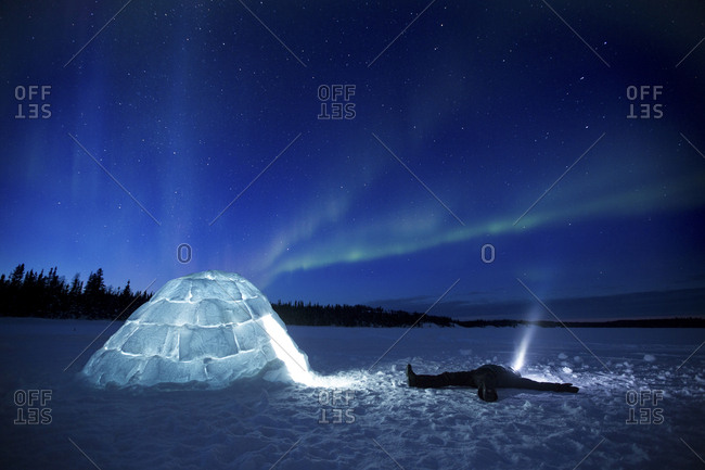 Person watching Aurora Borealis next to igloo, Yellowknife