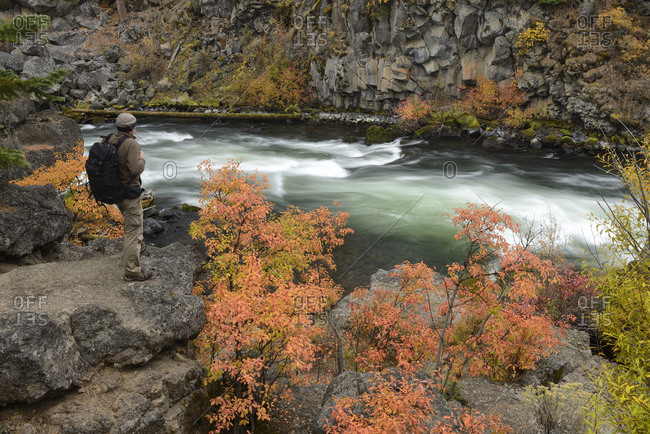 Man with backpack along Deschutes River at Dillon Falls in fall