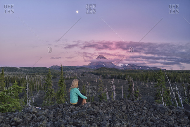 Woman watching Three Sisters Mountains in lava field on McKenzie Pass