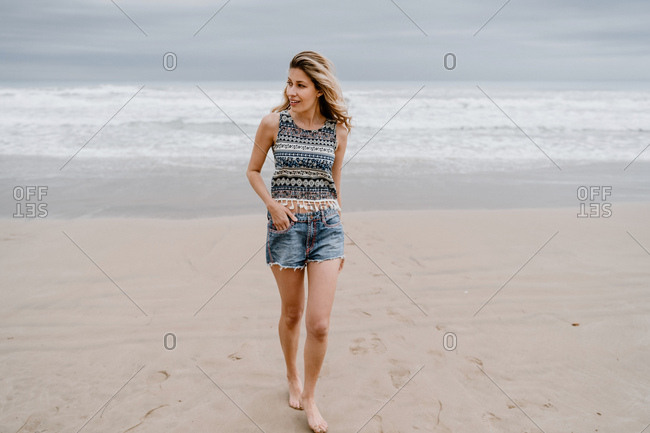Premium Photo | At sunset on the beach, a young woman has fun and jumps  near the water in a t-shirt and jeans with bare feet