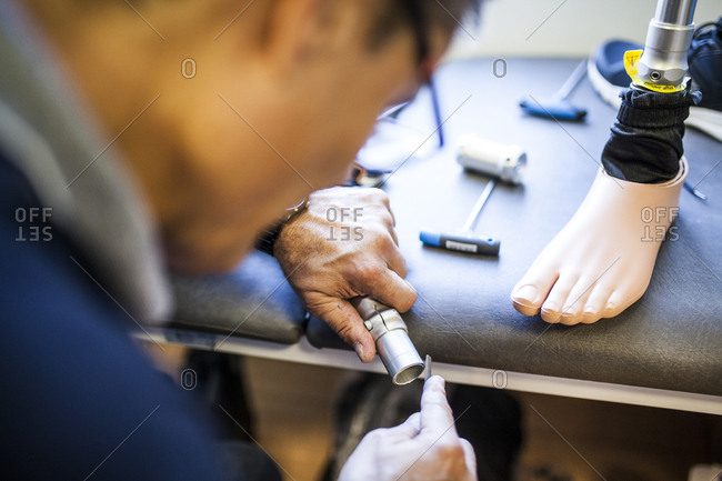 Prosthetic engineer reviewing the prosthesis of a patient and improving the material in his workshop