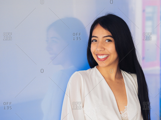 Attractive brunette long haired woman in light white lace clothing smiling looking at camera