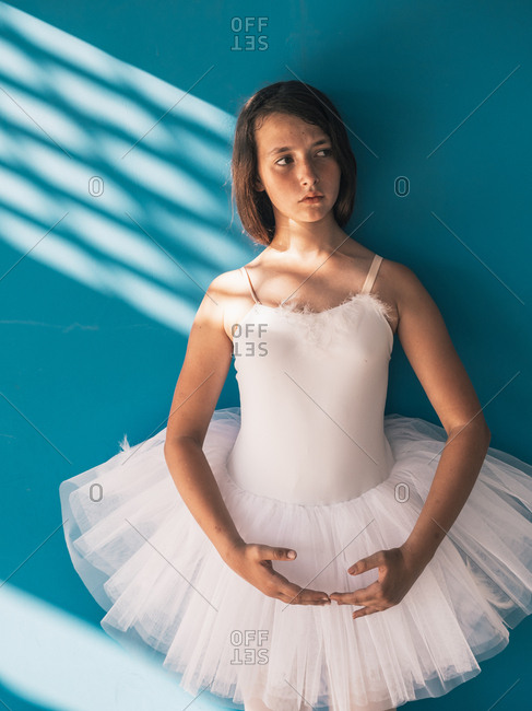 Ballerina standing with sad face near wall