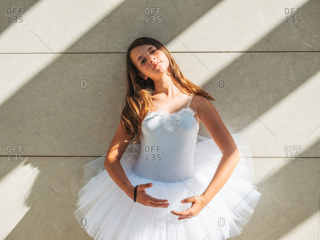 Ballerina standing in classical position near wall