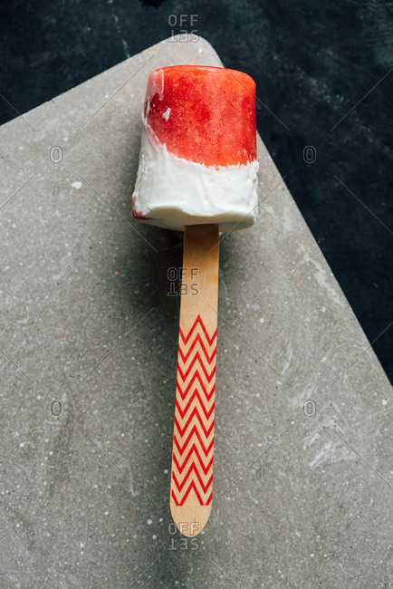 Close-up top view of watermelon and cream popsicle laying on fancy dish on dark background