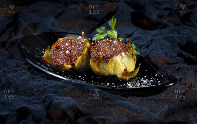 Tasty stuffed artichokes with salt on black background