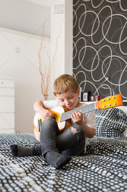 Young blonde boy playing toy guitar