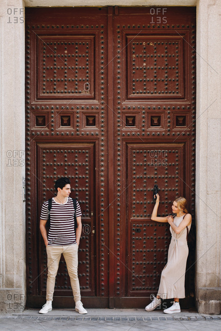 Young cheerful and playful couple in casual clothes posing in front of beautiful old door during dating outdoors