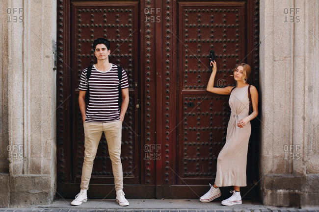 Young cheerful and playful couple in casual clothes posing in front of beautiful old door during dating outdoors