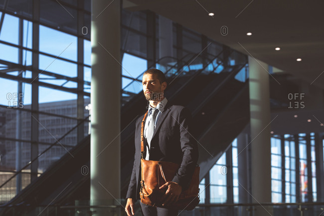 Side view of thoughtful businessman with office bag looking away in a modern office building