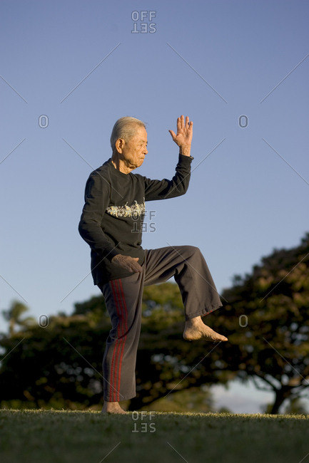 United States, Hawaii, Honolulu - June 30, 2005: An elderly man, age 89, performs his daily Tai Chi regimen at Magic Island park in Honolulu.
