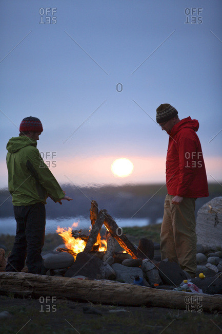 Two men stand around a camp fire on The Lost Coast, California.