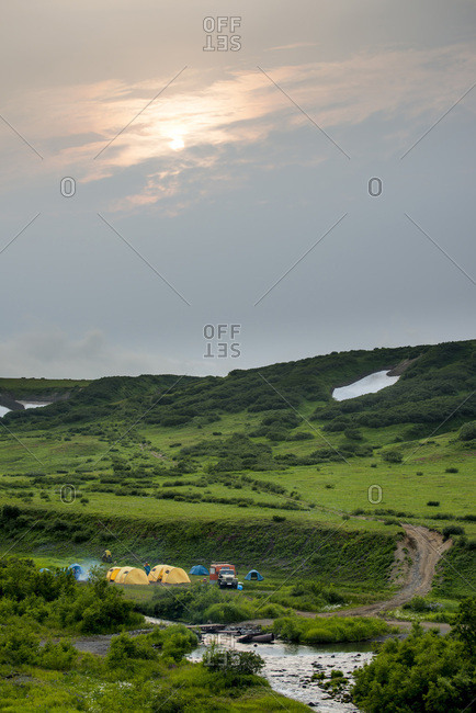 Tents and large trucks in wilderness by a river.  Kamchatka, Russia