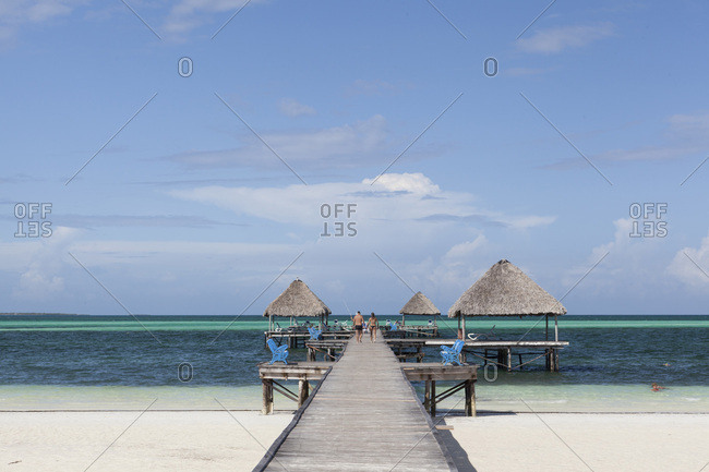 Couple walking on a wooden jetty on a the pristine tropical beach in Cayo Guillermo. Cuba