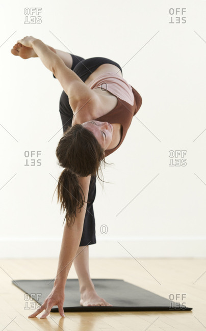 A woman practices yoga in a studio.
