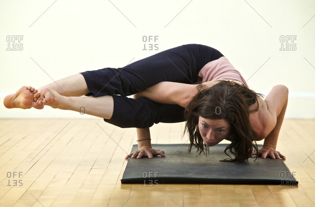 A woman practices yoga in a studio.