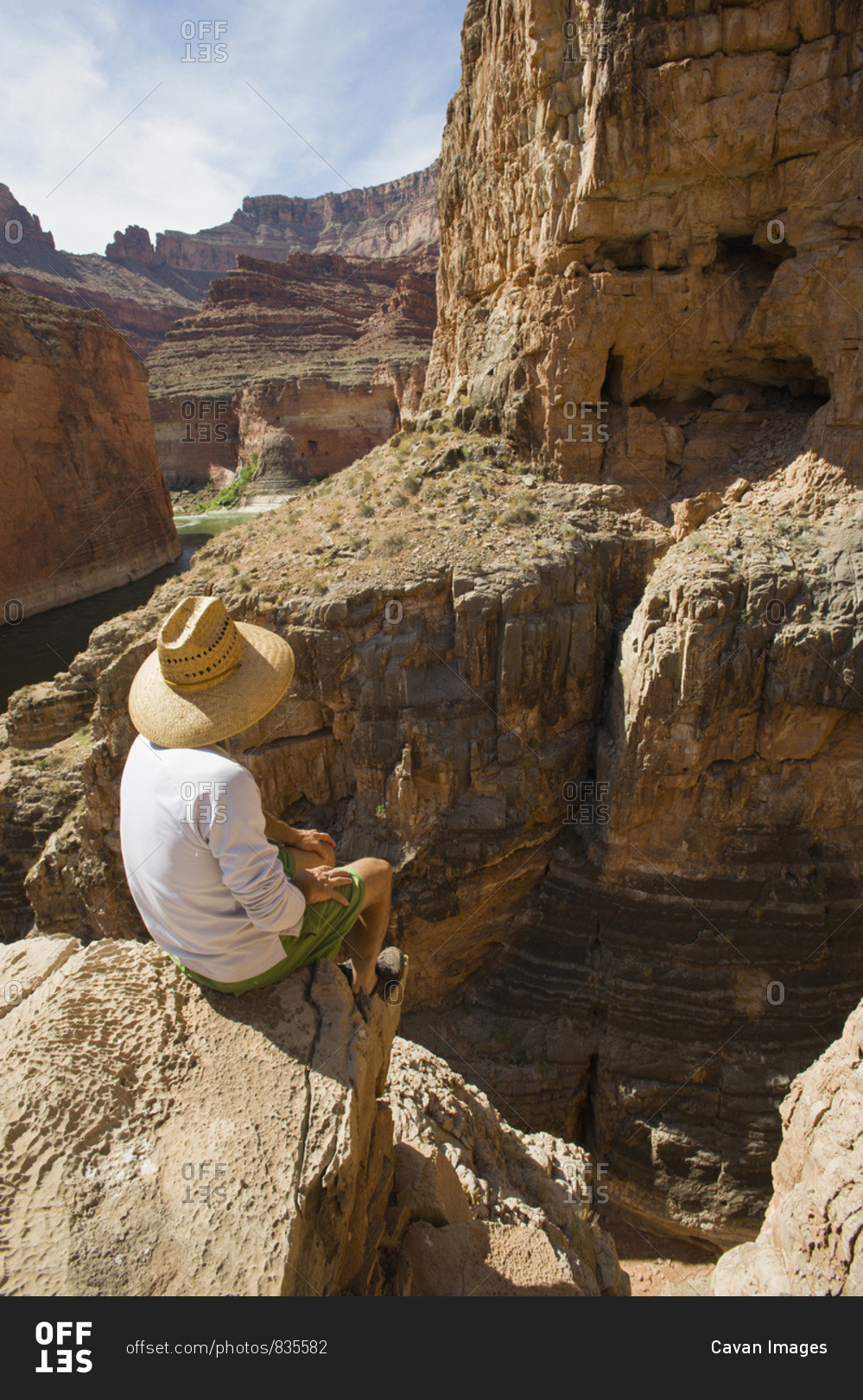 A man sits high on the rim of South Canyon, part of the Grand Canyon in Arizona.