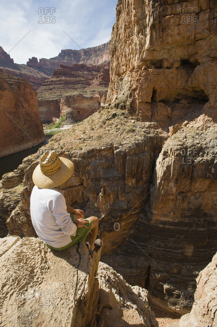 A man sits high on the rim of South Canyon, part of the Grand Canyon in Arizona.