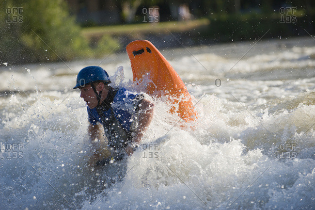 A male whitewater kayaker playboats on the Missoula playwave.