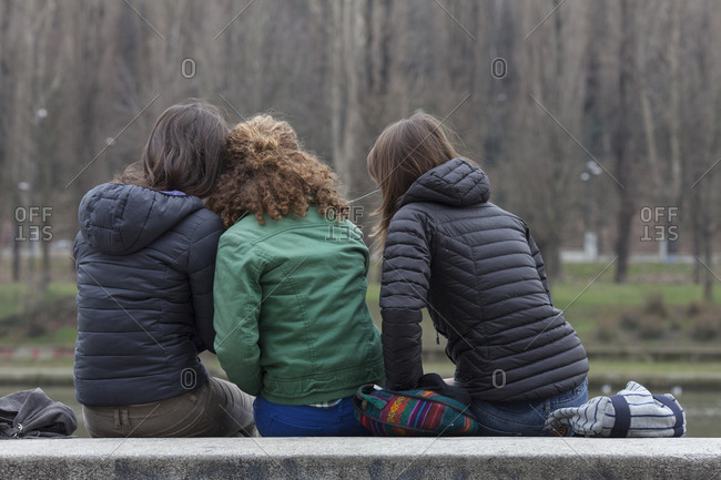 Teen girls relax on bench, sharing music