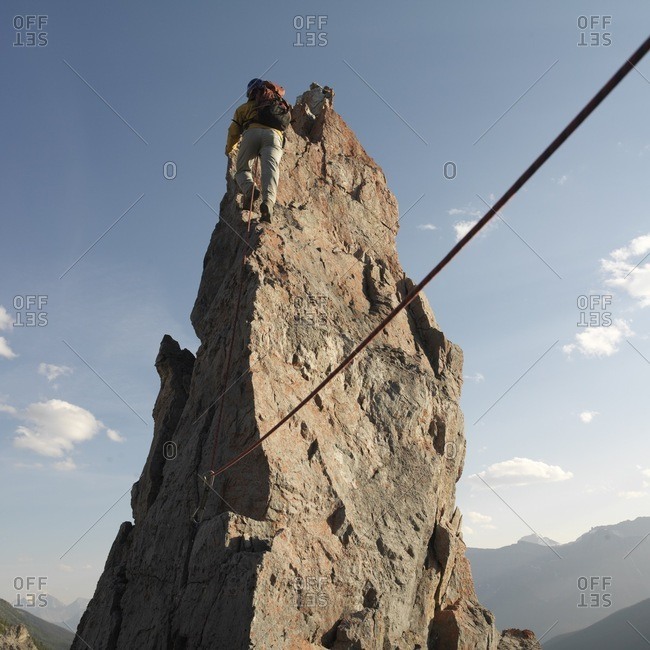 Climber ascends pinnacle above mountain range