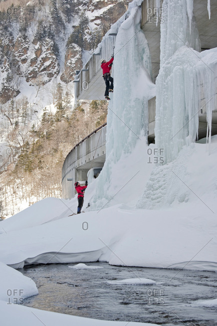 A man is belayed while climbing an ice pillar on a highway in Sounkyo Gorge, Daisetsuzan National Park, Hokkaido, Japan.