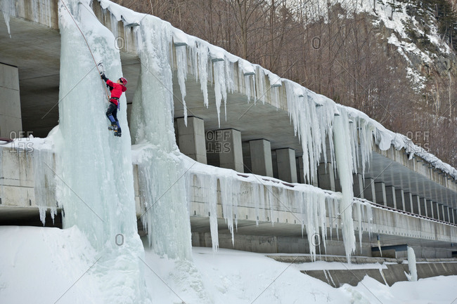 A woman is climbing an ice pillar on a highway in Sounkyo Gorge, Daisetsuzan National Park, Hokkaido, Japan.