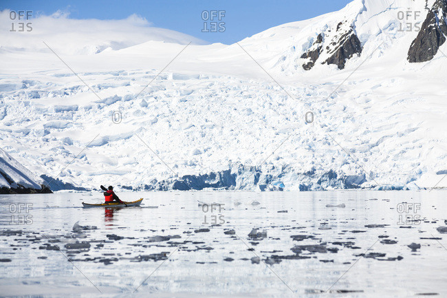 A man is paddling a sea kayak in Graham Passage, Antarctic Peninsula, Antarctica.