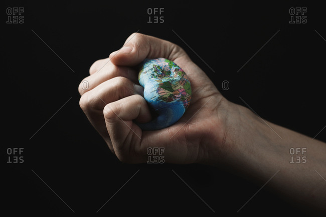 Closeup of a young caucasian man smashing a world globe in his hand