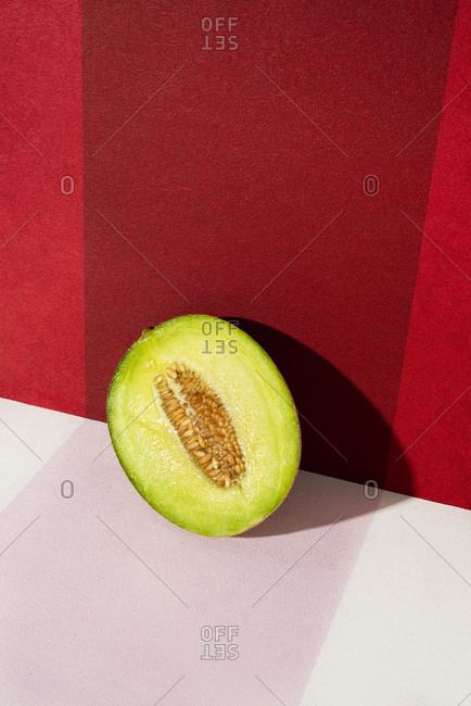 Closeup of a slice of galia melon on a white and red background