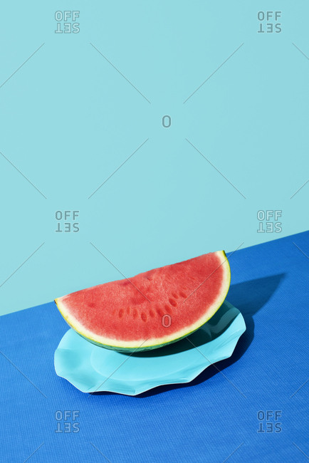 Closeup of a slice of a colorful red ripe watermelon on a background with two different shades of blue