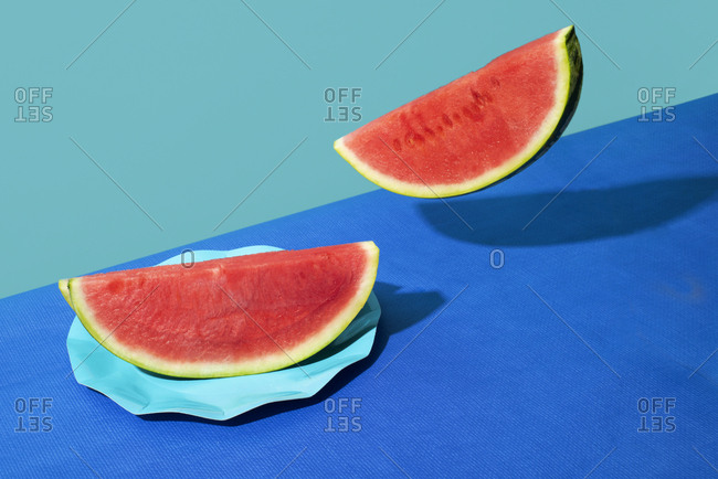 Closeup of some slices of a colorful red ripe watermelon on a background with two different shades of blue