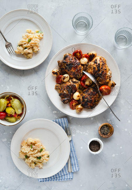 Roasted chicken thighs with pearl onions and tomatoes served with mashed potatoes and pickled peppers