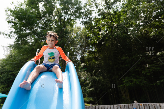 Little boy sliding down pool slide