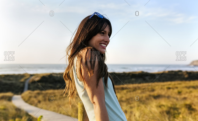 Portrait of a smiling woman in dunes at sunset