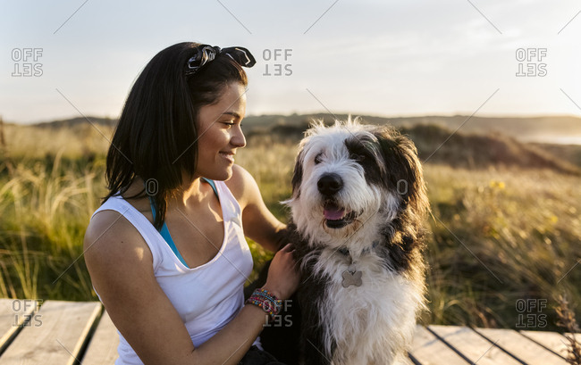 Smiling woman with dog on boardwalk in dunes