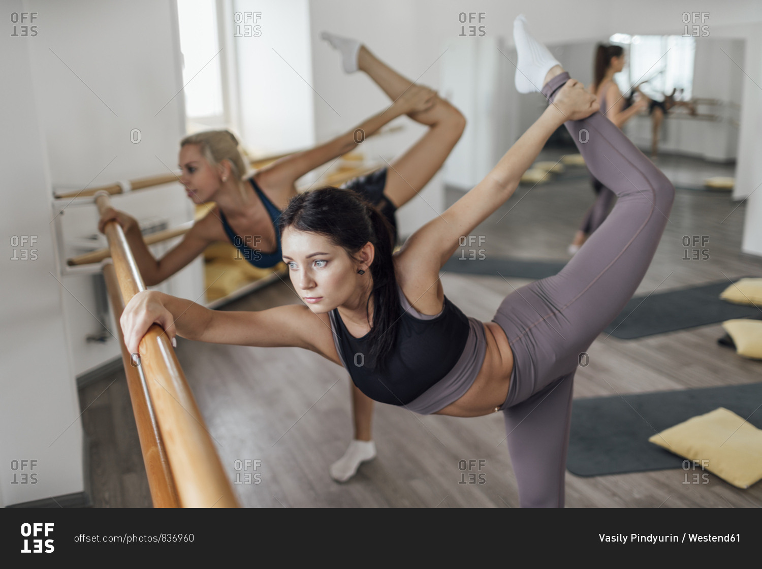 Two young women doing barre workout in gym