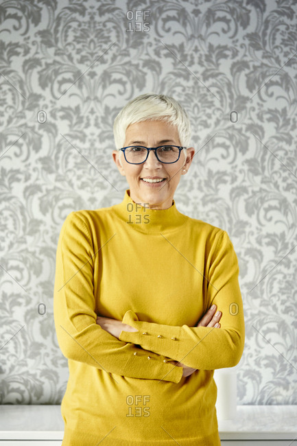 Portrait of a senior woman against a patterned wallpaper