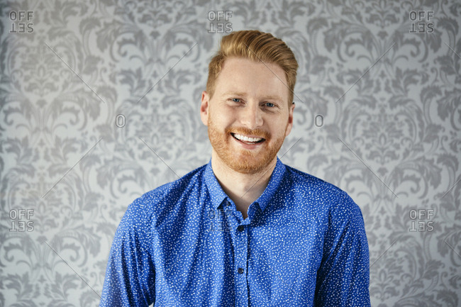 Portrait of a happy man in front of patterned wallpaper