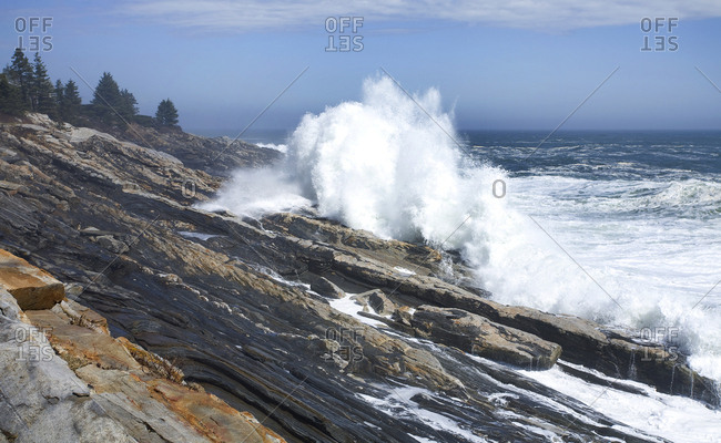 Waves froth onto rugged granite shoreline in Maine after offshore storm